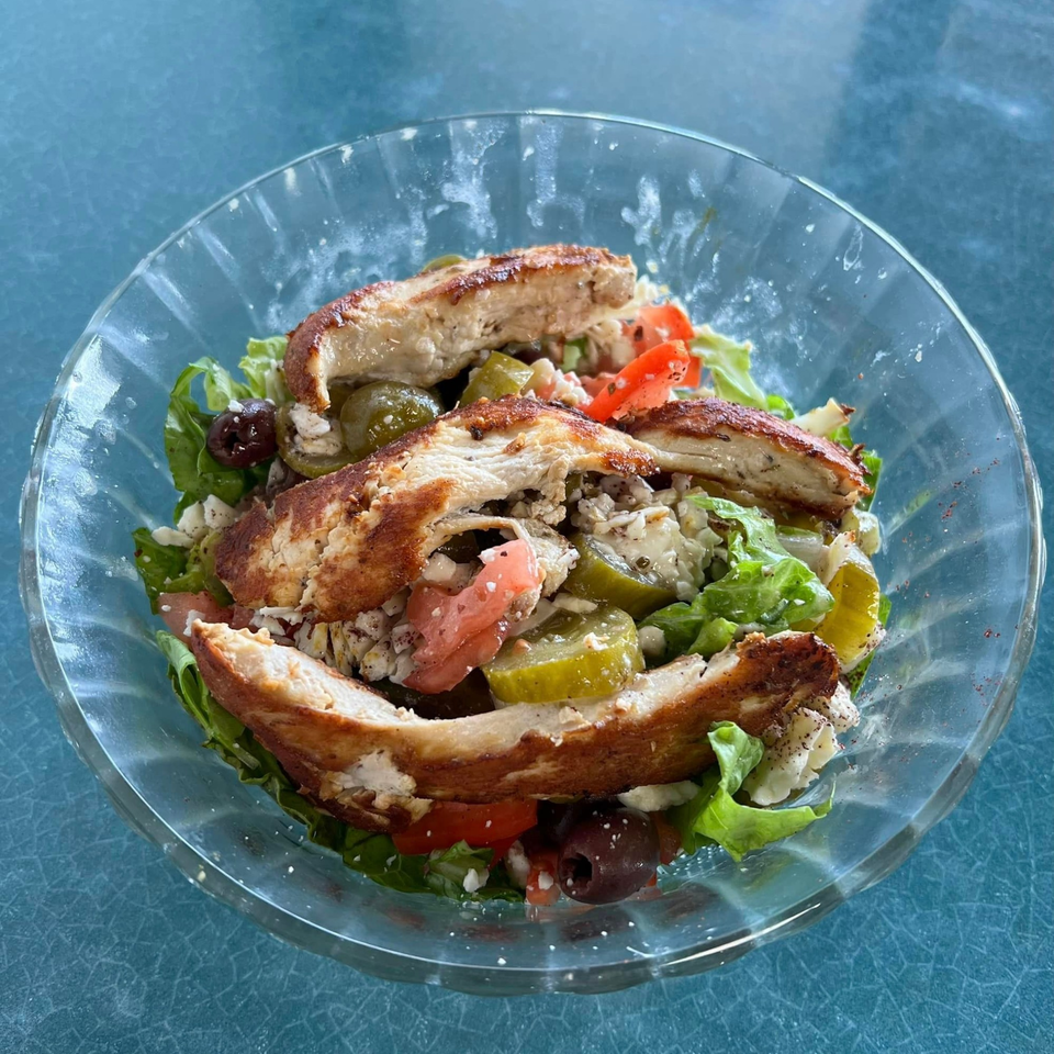 Mediterranean salad with grilled chicken, lettuce, tomatoes, olives, pickles, and feta cheese.